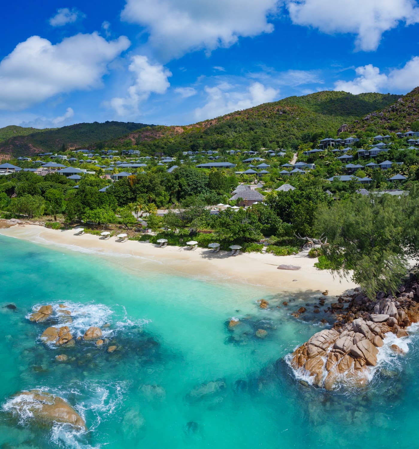 The sea is magically blue and villas peek out of the emerald vegetation at Raffles Seychelles